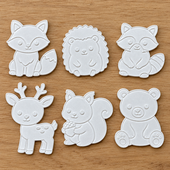Six white 3D-printed woodland animal coloring pieces arranged on a wood surface